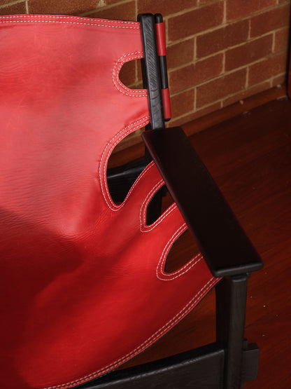 Replica Sergio Rodrigues Kilin lounge chair in red leather with black wooden frame with brick wall background