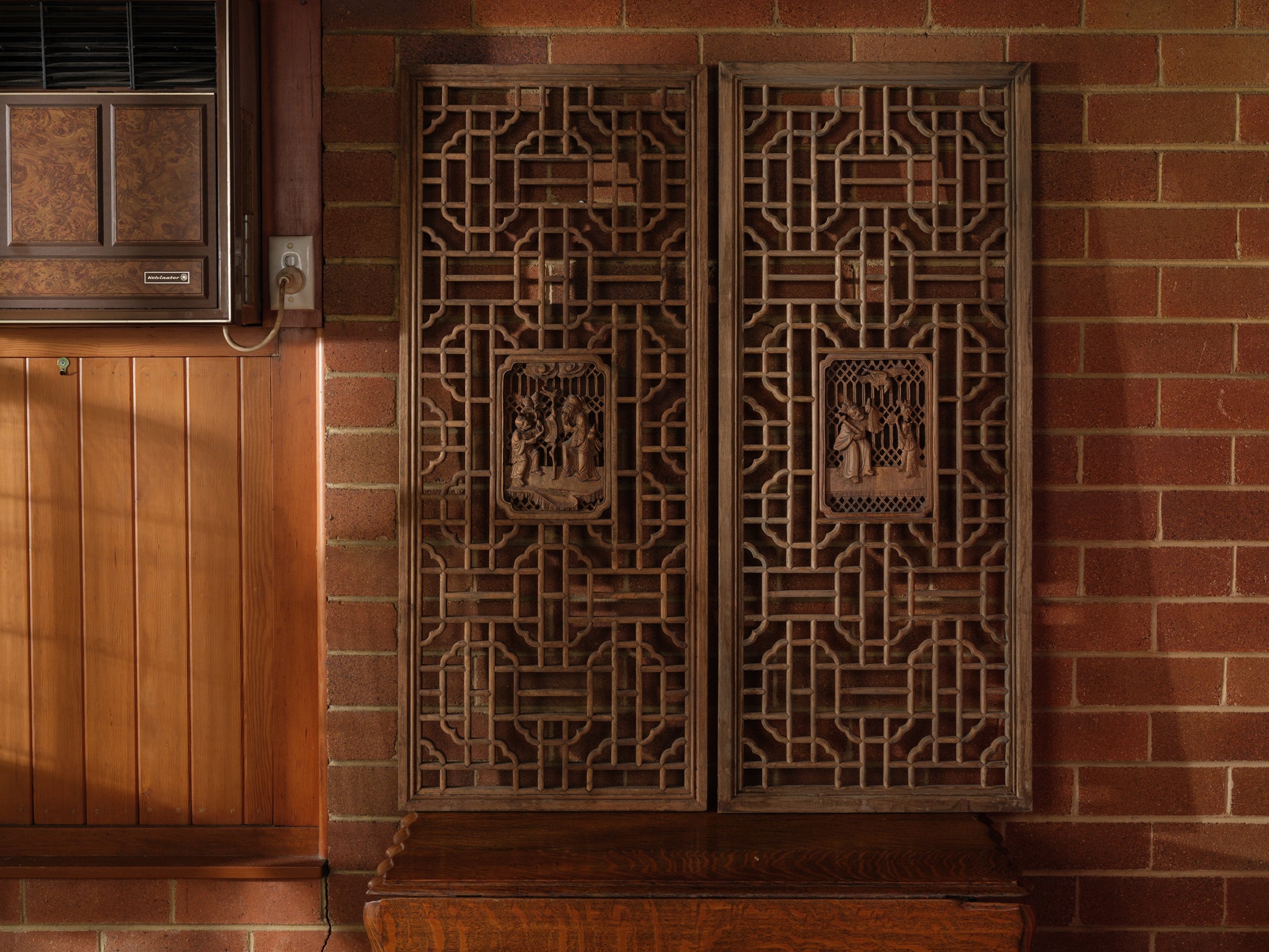 Pair of antique Chinese lattice panels with intricate geometric fretwork and carved scholar scenes in relief at the center.