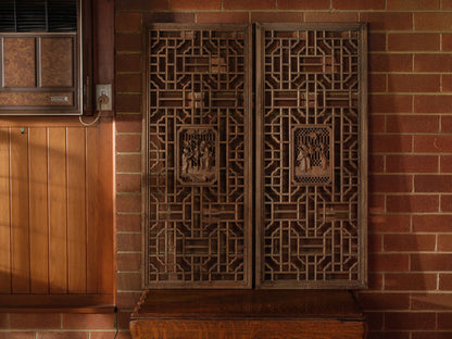 Pair of antique Chinese lattice panels with intricate geometric fretwork and carved scholar scenes in relief at the center.