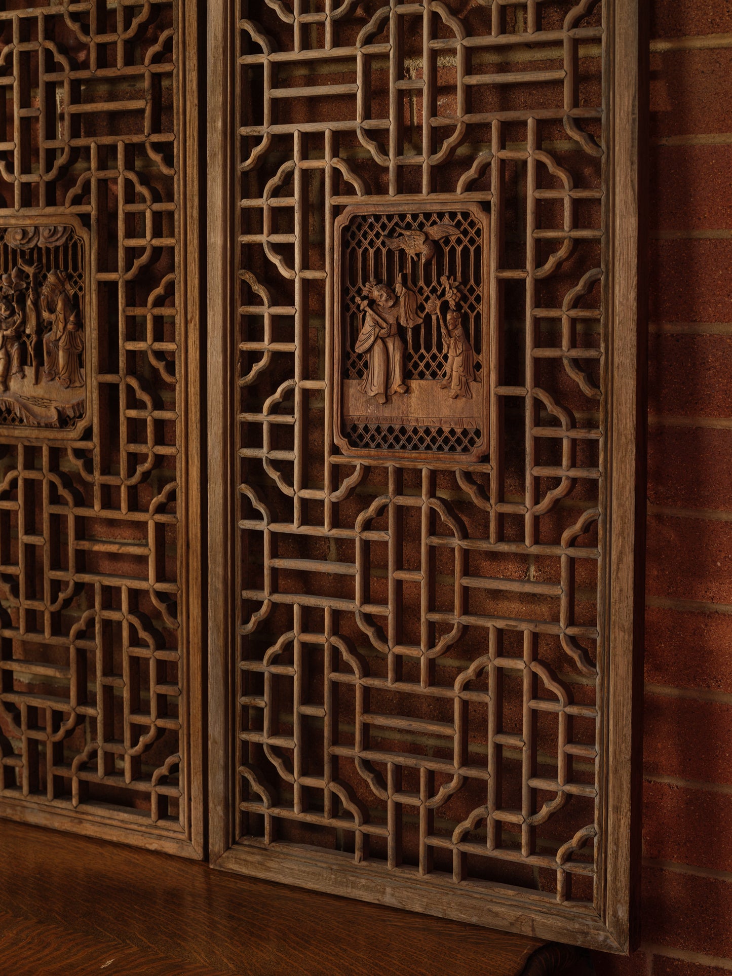 Pair of antique Chinese lattice panels with intricate geometric fretwork and carved scholar scenes in relief at the center.