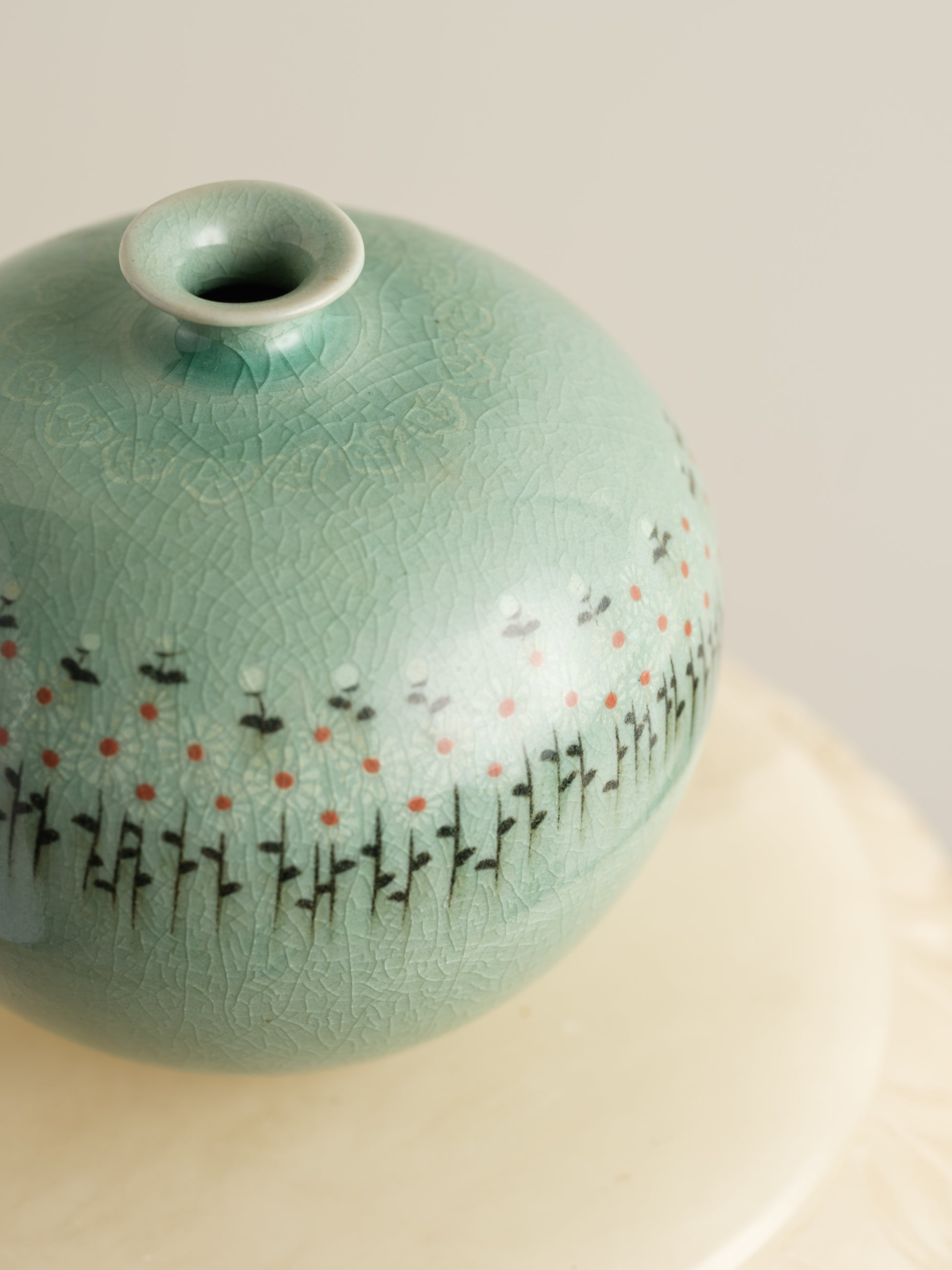 Small celadon bud vase in jade green glaze with hand-painted meadow flower motif around the shoulder.
