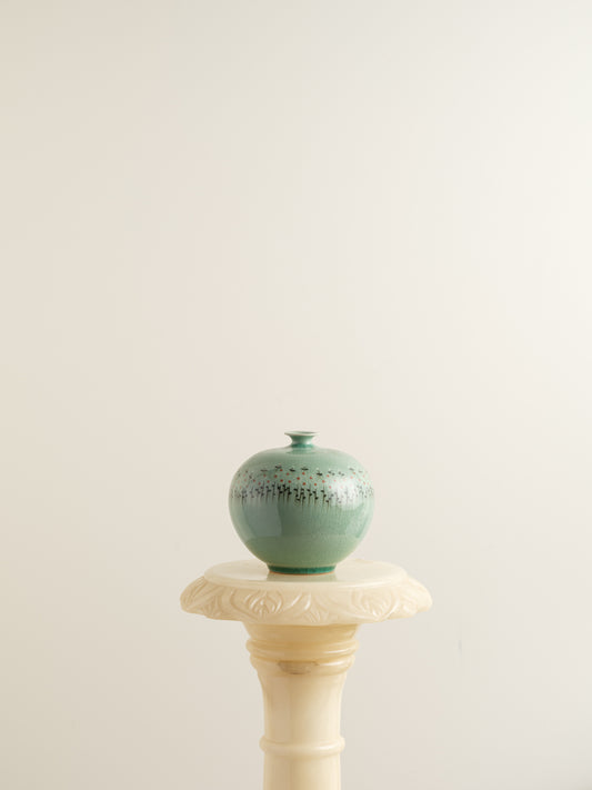 Small celadon bud vase in jade green glaze with hand-painted meadow flower motif around the shoulder.