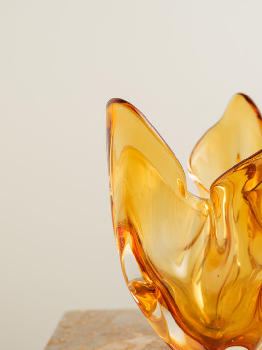 Amber-orange art glass vase with petal-like sculptural form and fluid edges.