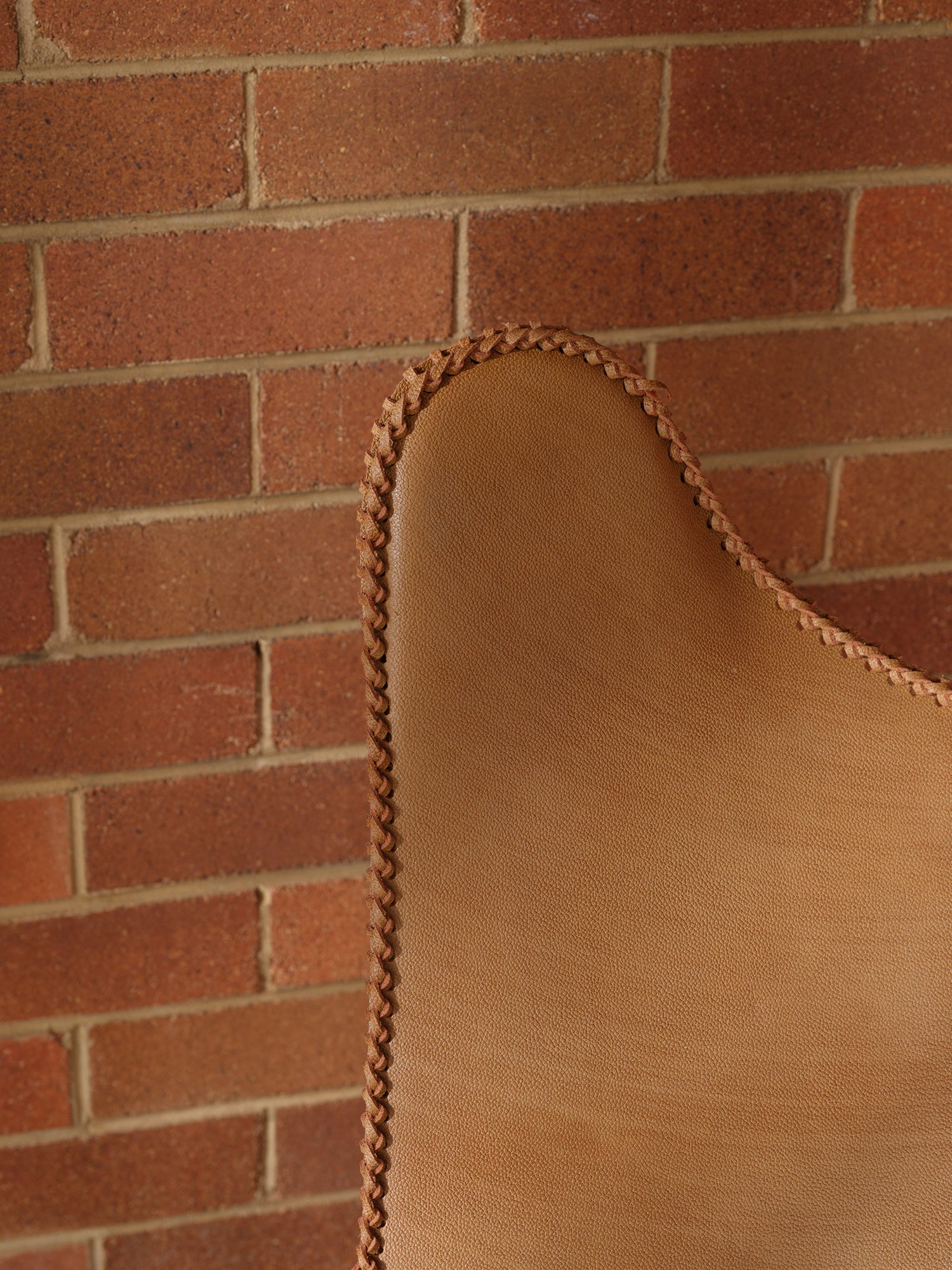Tan suede butterfly lounge chair with stitched leather seat and metal frame, mid-century modern style