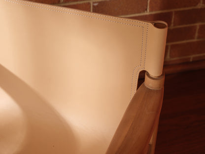 Tanned leather armchair with natural wood frame, modern accent seating