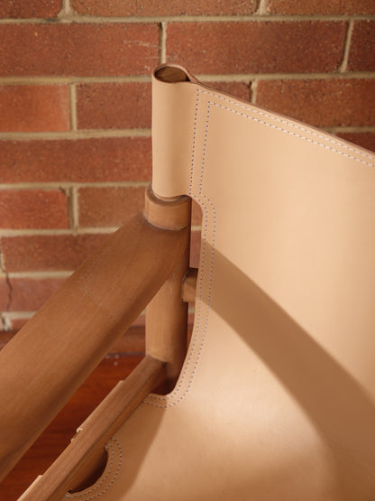 Tanned leather armchair with natural wood frame, modern accent seating