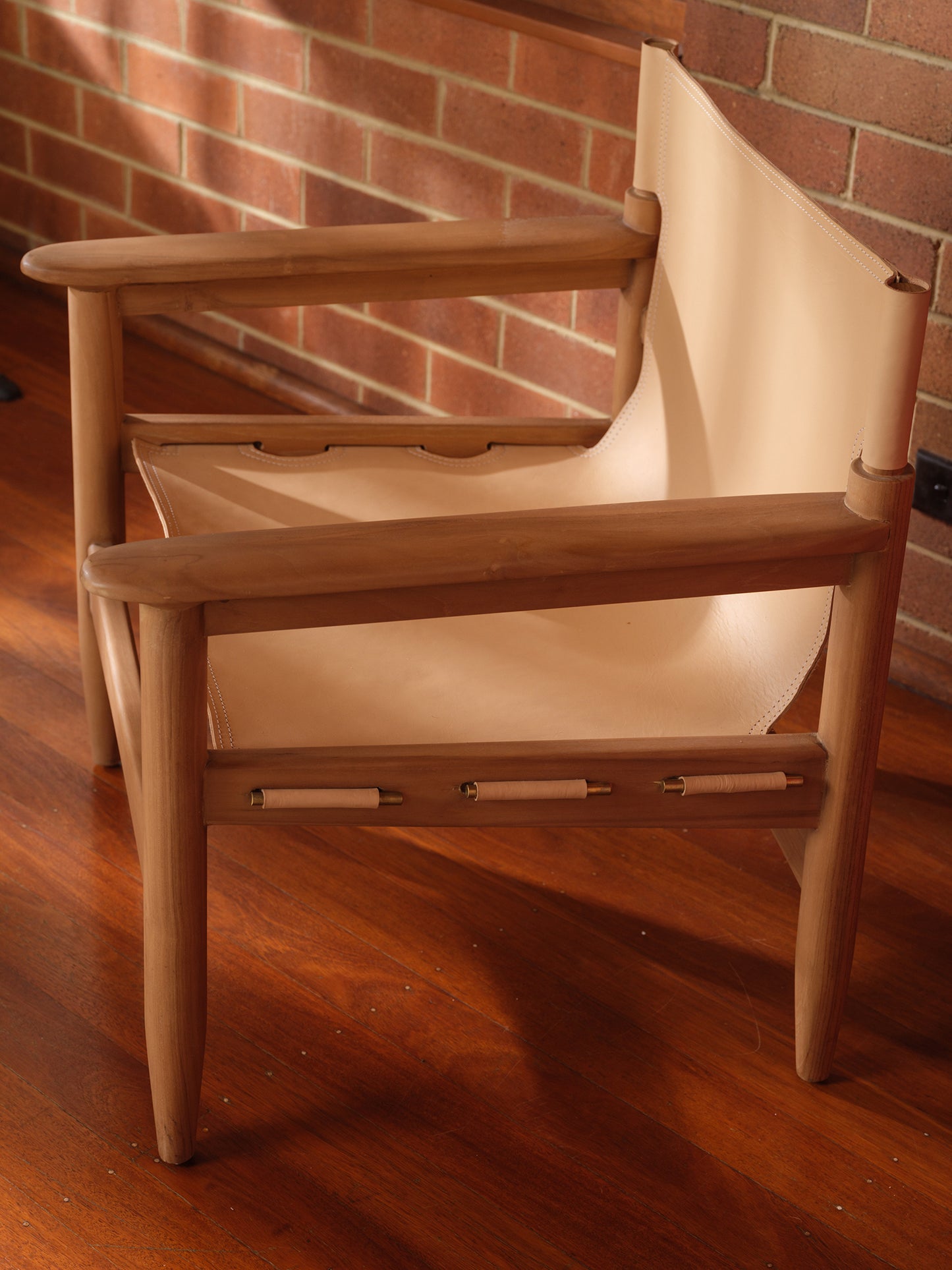 Tanned leather armchair with natural wood frame, modern accent seating