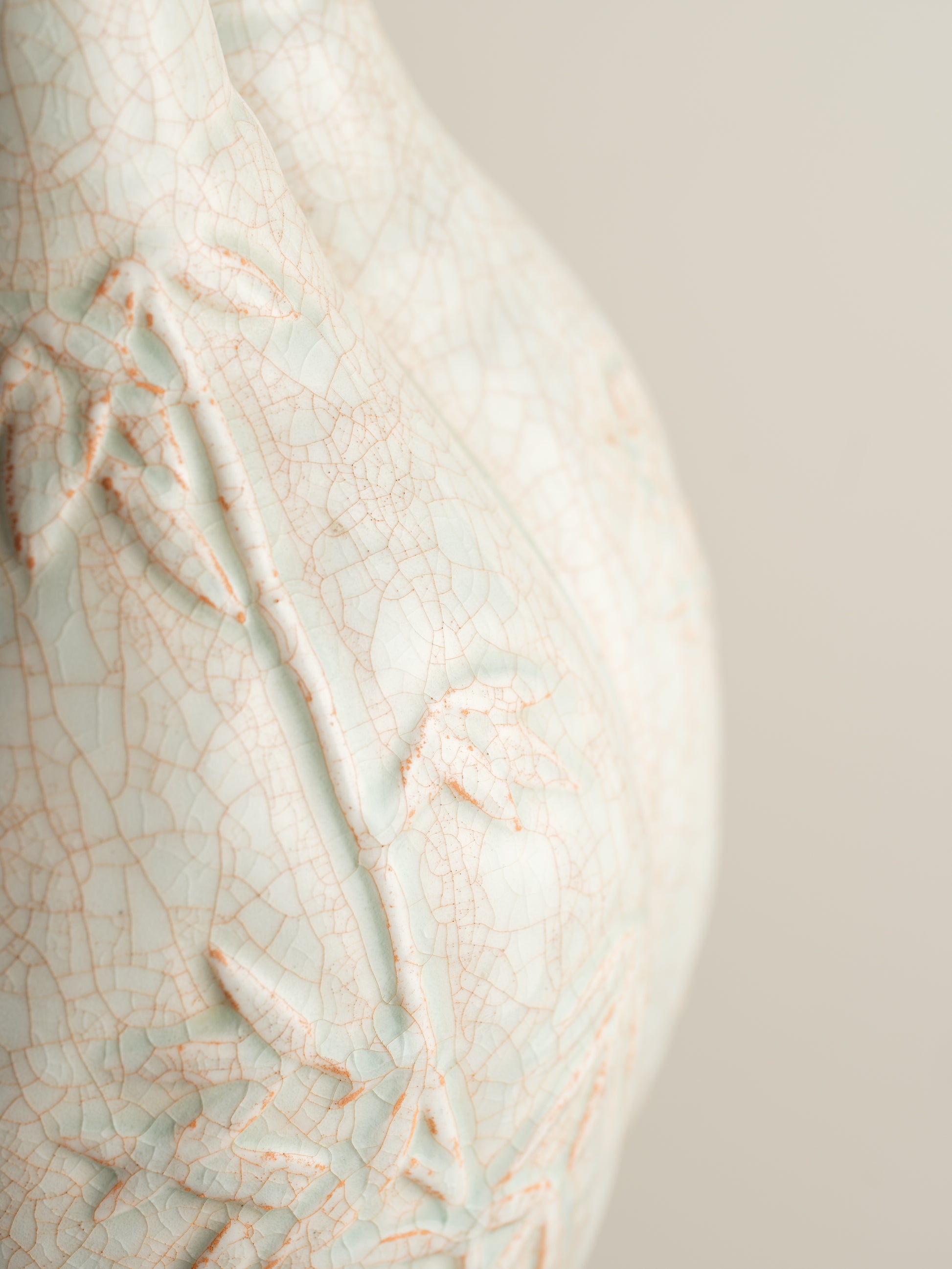 Celadon vase with three joined necks, embossed floral and bamboo motifs, and pale jade crackle glaze with russet tones.