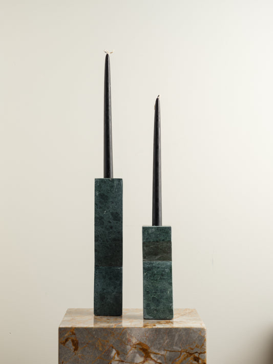Pair of green marble candle holders with tall rectangular columns and black taper candles.