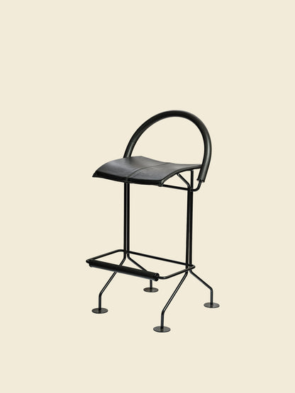Vintage modern metal barstool with black leather seat and curved backrest.