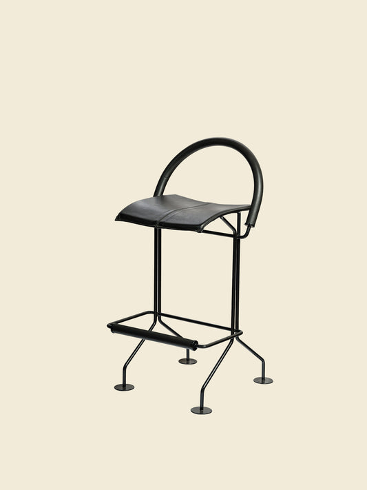 Vintage modern metal barstool with black leather seat and curved backrest.
