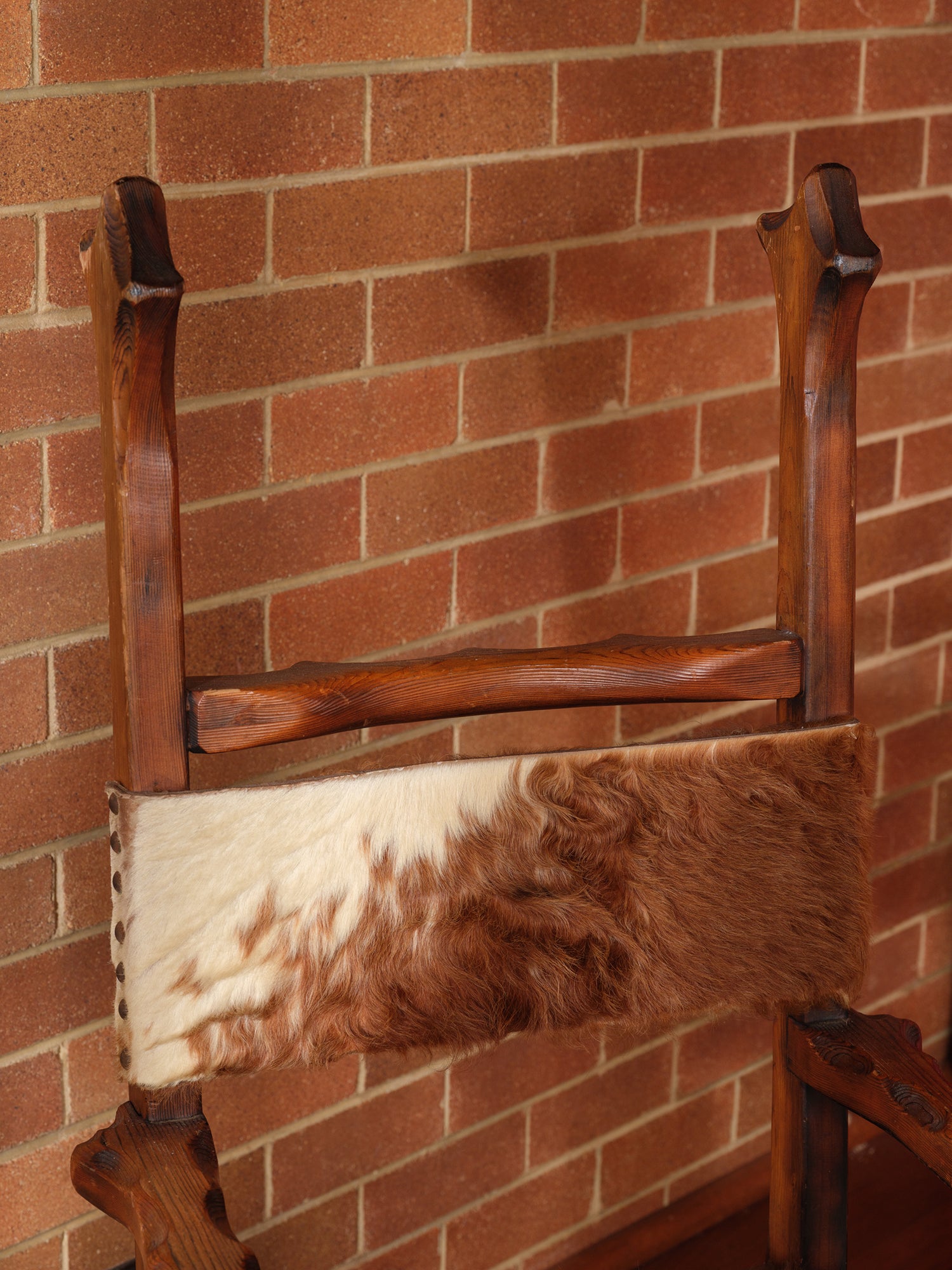 Wooden chair with a fur cushion against a brick wall