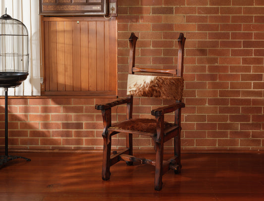 Wooden chair with leather seat against a brick wall