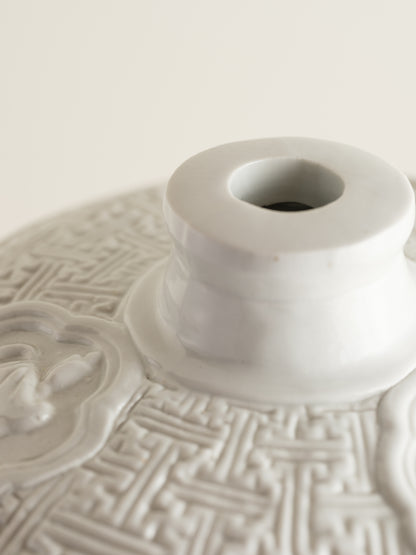 White porcelain meiping vase featuring intricate dragon relief motifs and geometric borders.