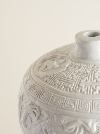 White porcelain meiping vase featuring intricate dragon relief motifs and geometric borders.