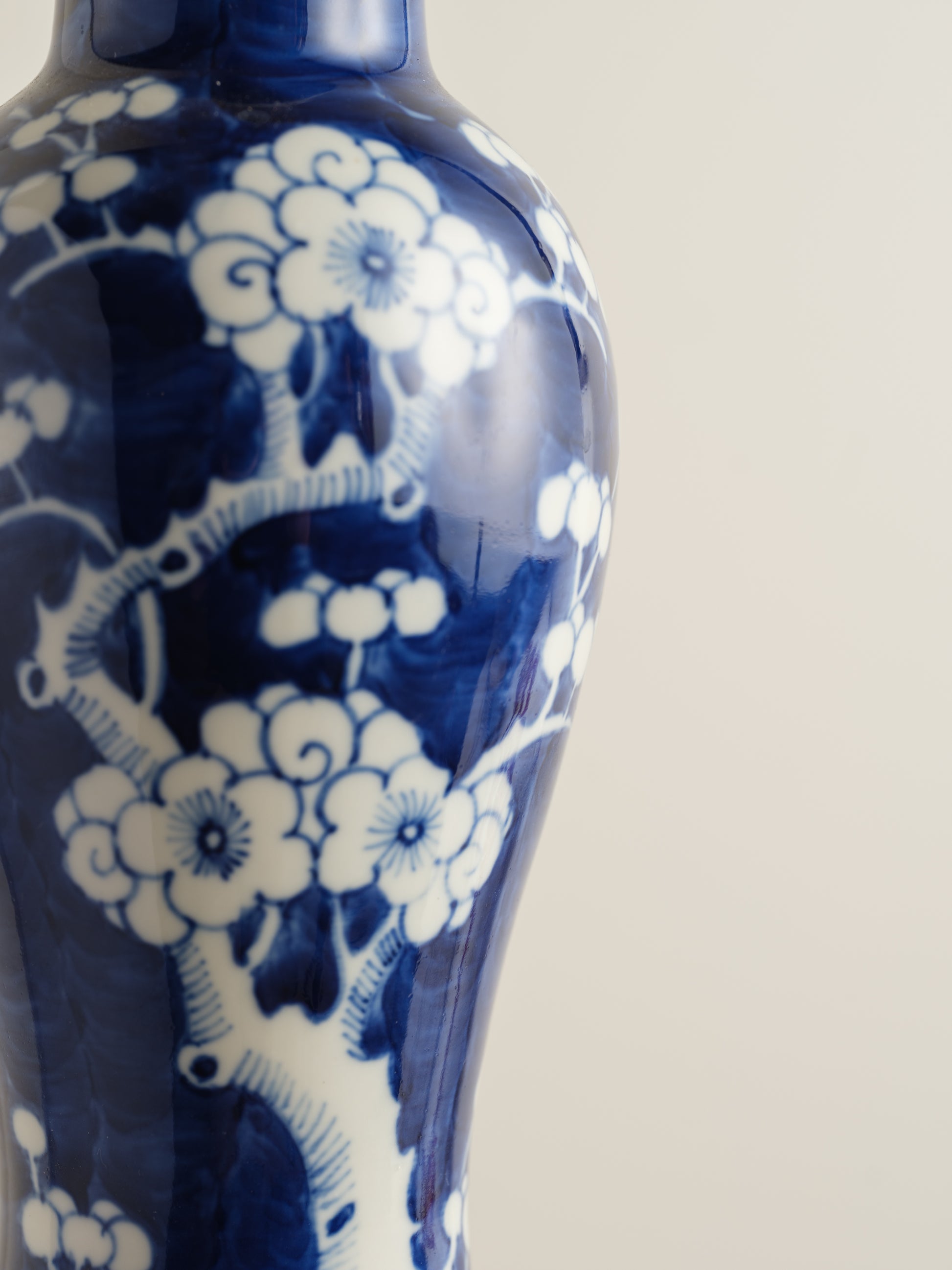 Porcelain vase in deep indigo glaze featuring hand-painted white plum blossoms.
